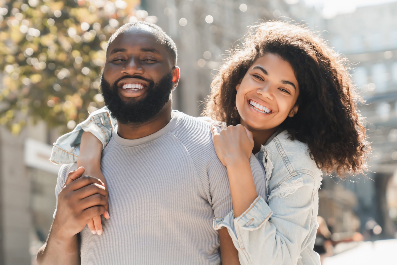 Trust relationship love and bonding concept.Young african woman hugging embracing her lover male man while walking on romantic date in city park together.