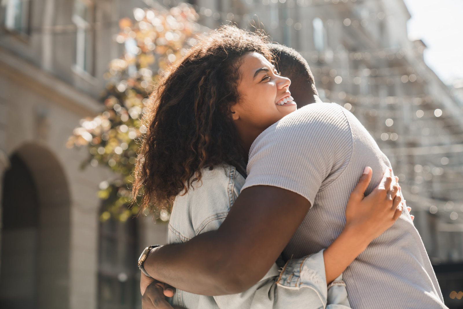 Two young friends african-american couple hugging embracing on romantic date meeting together outdoors. First meeting, true feelings, love, parting concept.